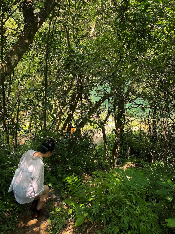 Person wearing white shirt making their way down the hidden trail to Huiyao Waterfall